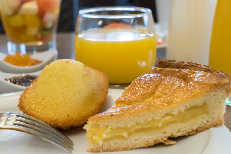 gâteau basque et madeleine devant un verre de jus d'orange servis au Sure Hotel Biarritz Aéroport