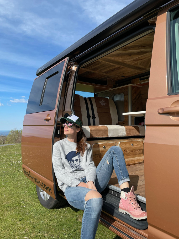 Femme prenant le soleil assise dans un véhicule aménagé Woody Van