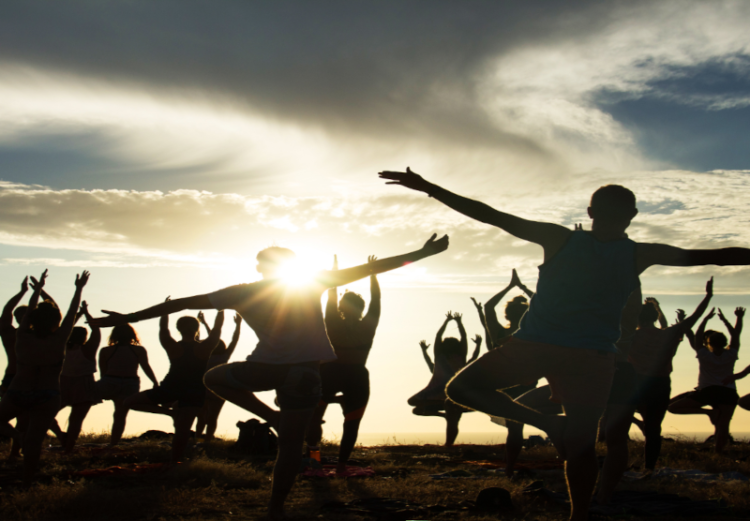Participants à des cours de yoga en extérieur au soleil couchant