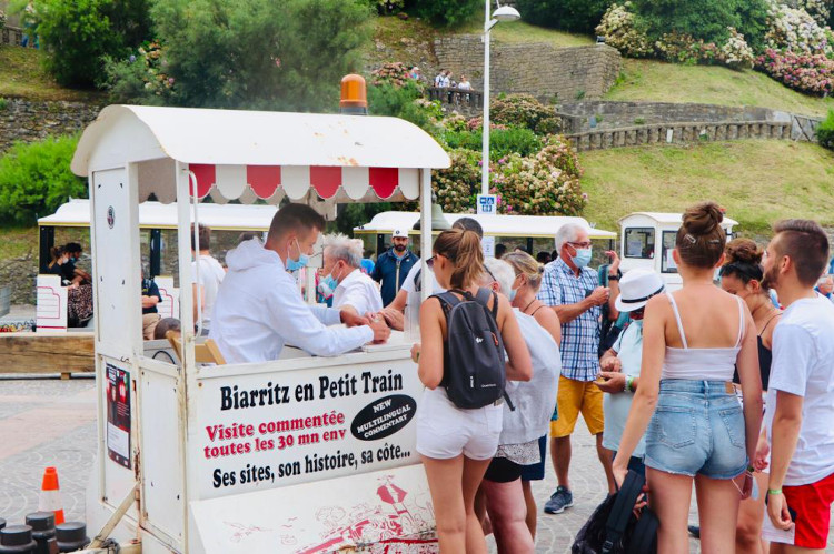 Des touristes achètent des billets pour monter à bord du Petit Train de Biarritz